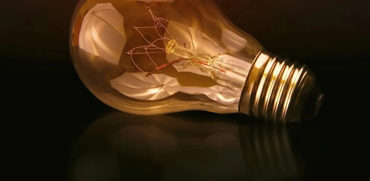 A glowing filament lightbulb on a dark surface
