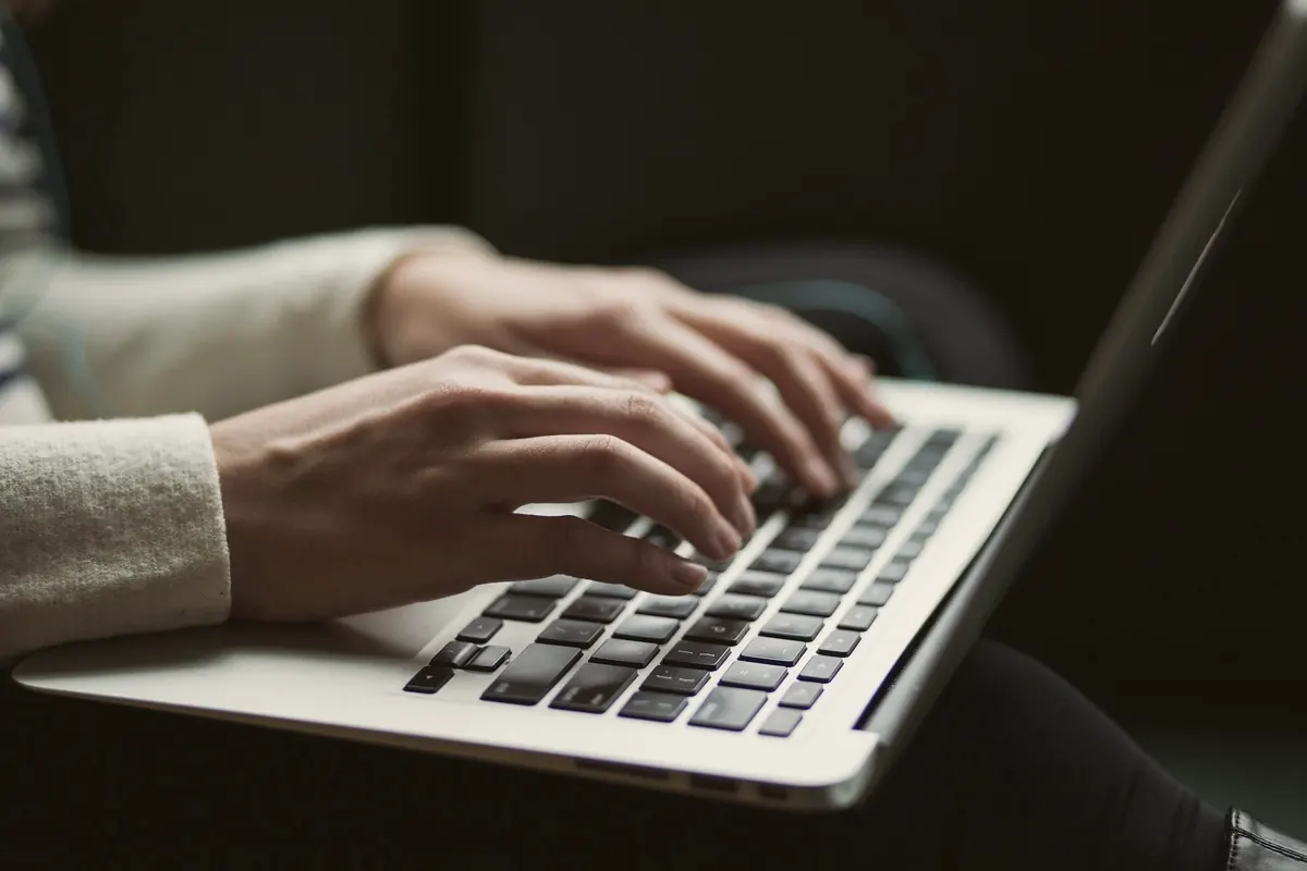 Hands typing on a laptop in a dark room